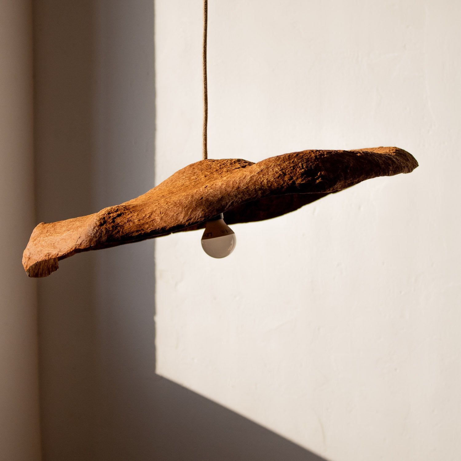 Decorative 50 cm pendant light  from paper mache with a natural texture design in teracotta color against a neutral background with natural light