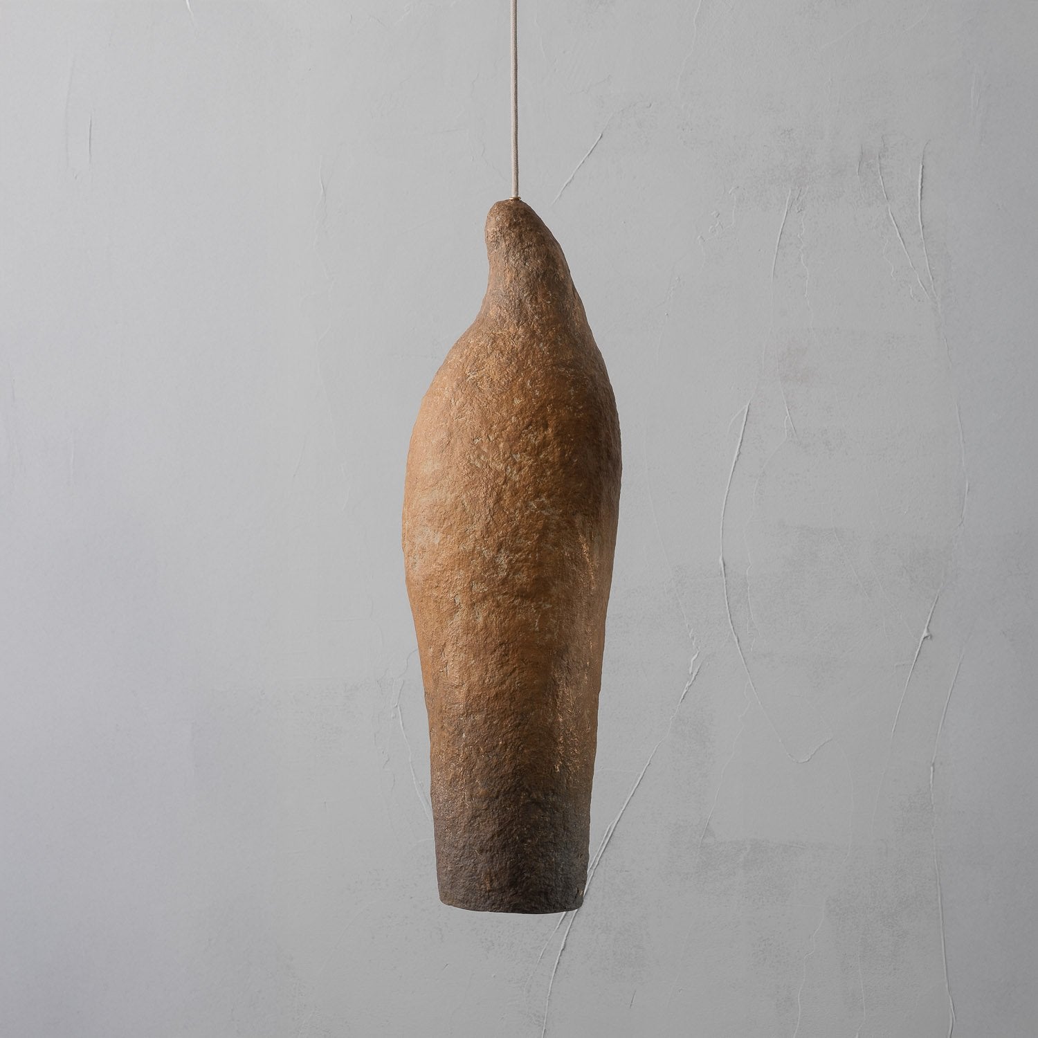 orange brown Textured wabi sabi pendant light fixture made from paper mache on a gray background
