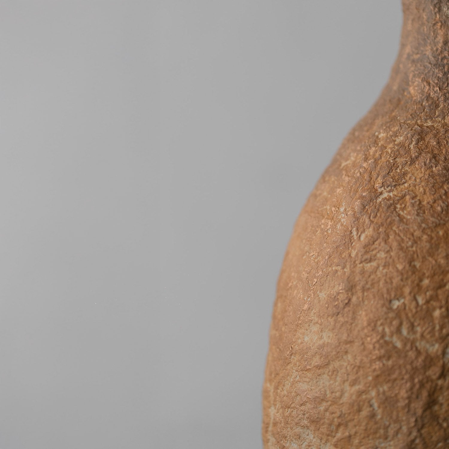 Close-up of a textured brown pendant against a gray background