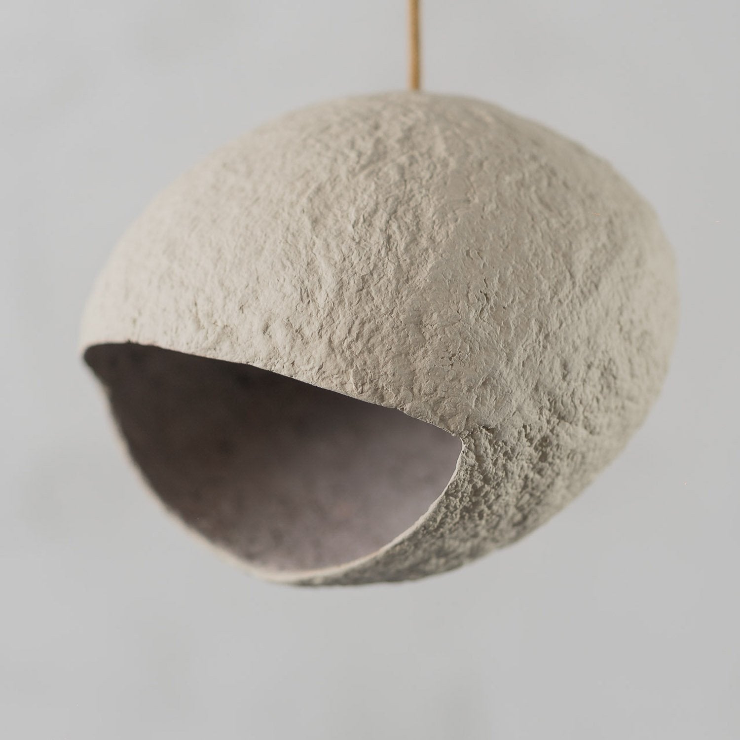Textured spherical hanging light object on light beige color on a plain background