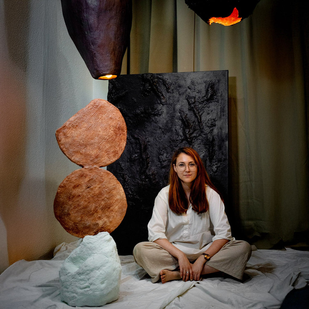 Person sitting in front of artistic plaster sculptures and abstract art in a studio setting