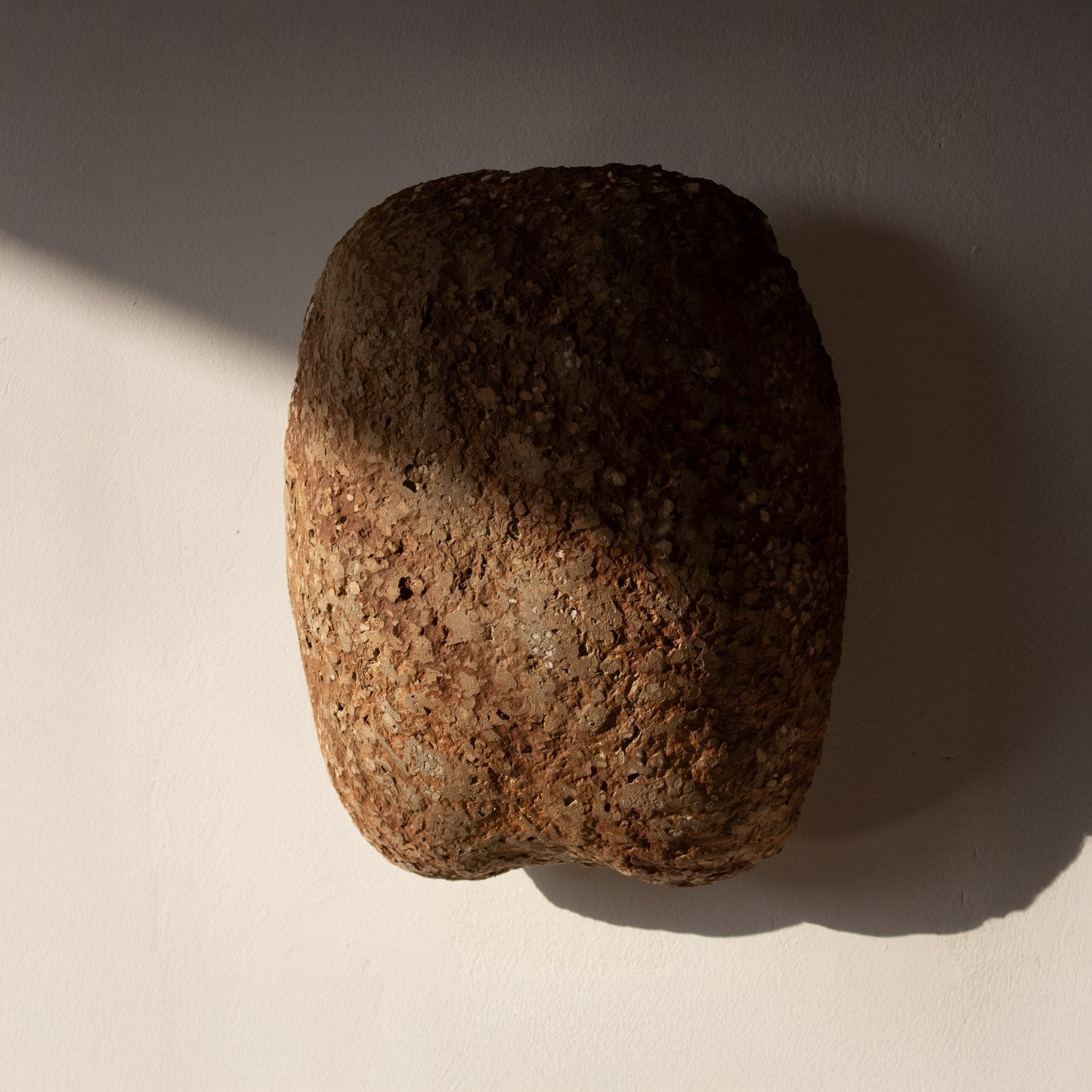 Orange Brown stone texture of a paper mache wall lamp on a beige surface with a soft shadow