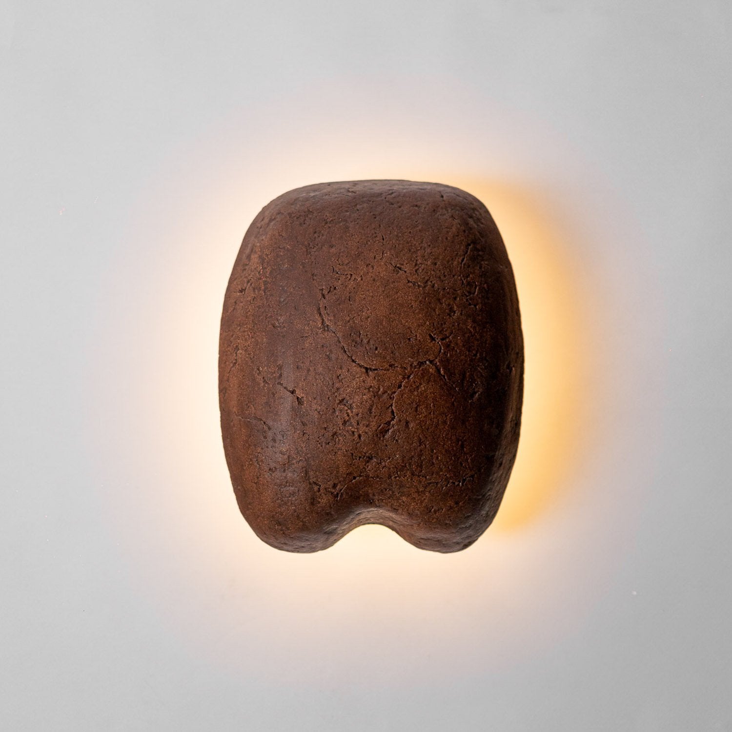 Brown Paper mache wall sconce with a textured surface on a light gray background